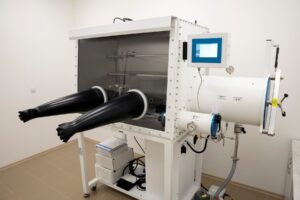A stainless steel glovebox used to handle sensitive materials in a controlled, inert-atmosphere laboratory.