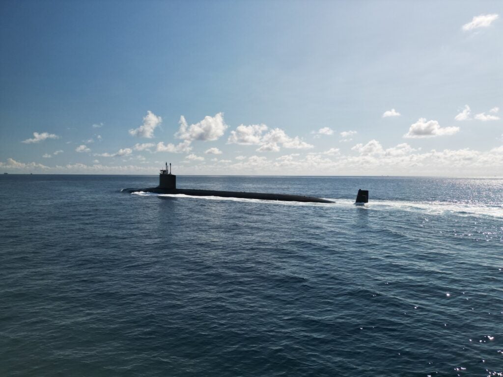 A naval ballistic missile submarine partially surfaced and underway in open ocean.