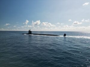 A naval ballistic missile submarine partially surfaced and underway in open ocean.