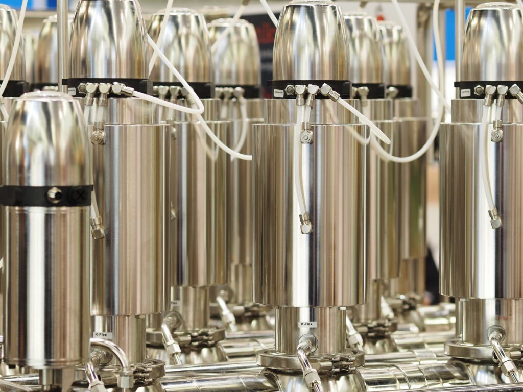 Rows of vertical cylindrical stainless steel centrifuge units arranged in an industrial cascade.