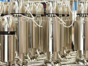 Rows of vertical cylindrical stainless steel centrifuge units arranged in an industrial cascade.