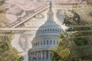 The U.S. Capitol dome framed by trees with an overlay of paper currency, symbolizing federal budget appropriations.